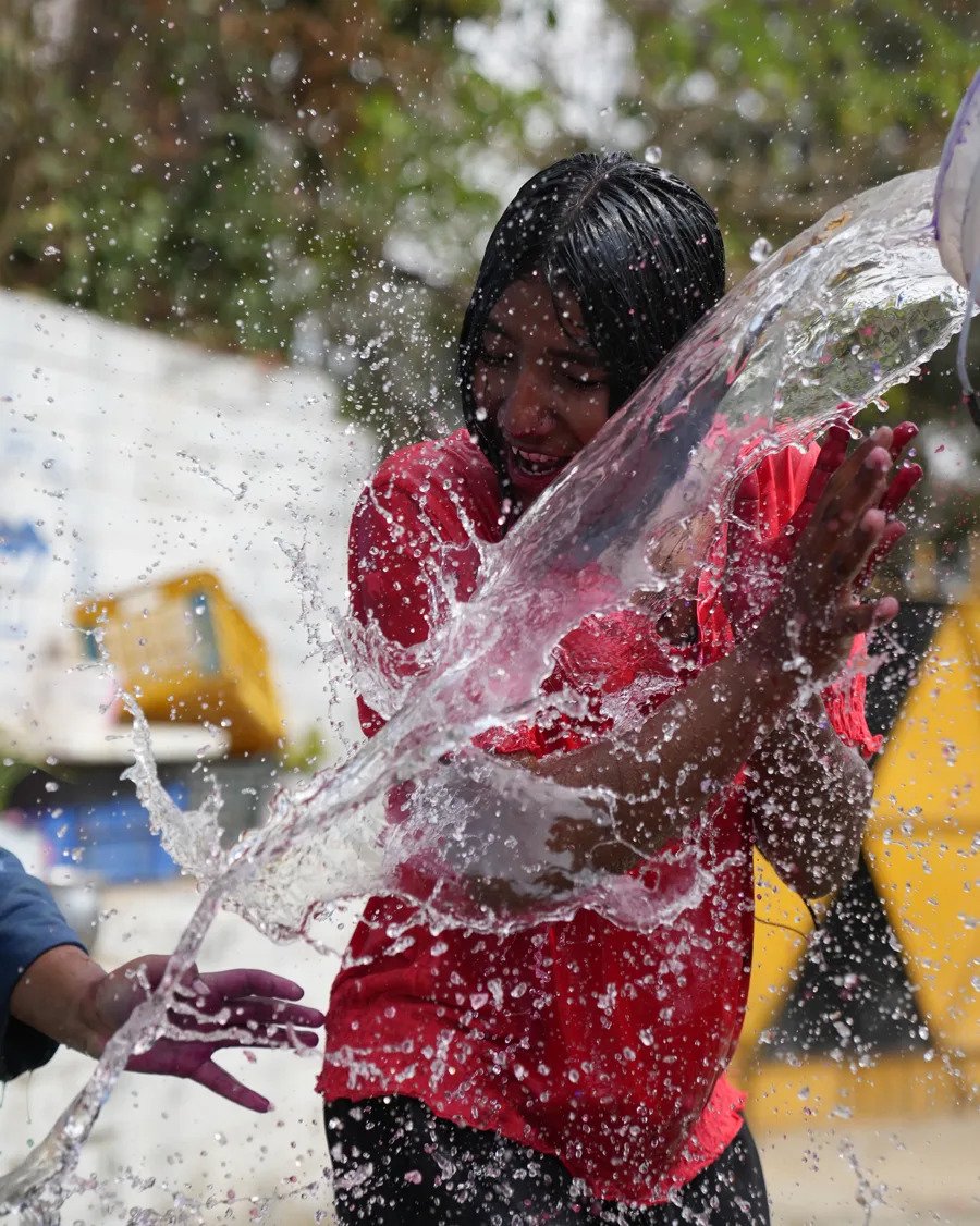 Kinder des Mountain Children's Home beim Holi-Fest: ein Mädchen wird mit Wasser übergossen, darunter ausgelassenes Feiern im Hof